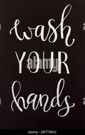 Chalk inscription WASH YOUR HANDS on a black chalkboard. Handwritten lettering Stock Photo