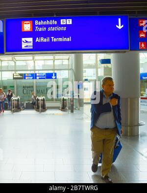 FRANKFURT AM MAIN, GERMANY - AUGUST 29, 2018: People with luggage exiting Frankfurt airport, Info board with direction signs above, Frankfurt am Main, Stock Photo