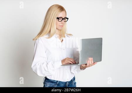 Confident Mature Business Woman Using Laptop At Studio Stock Photo