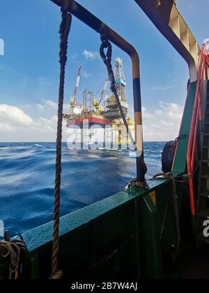 jack up rig and oil platform drilling at sea with rescue bot and crane from ship Stock Photo