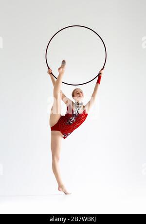 Professional athlete doing complicated gymnastic trick with hoop on white background Stock Photo