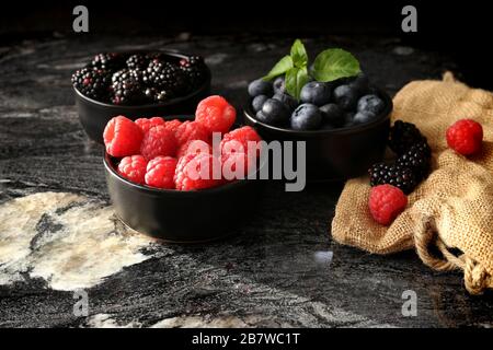 colorful black and red berries on black round plate with canvas on black stone table, top view Stock Photo