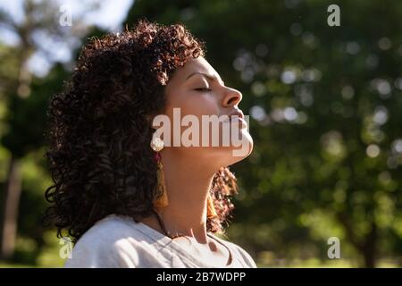 Young woman standing outside feeling the sun on her face Stock Photo