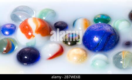 Multicolored marbles inside milk as abstract background Stock Photo