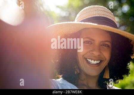 Smiling woman wearing a sun hat and talking selfies Stock Photo