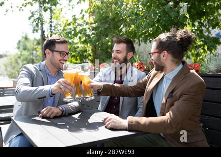 Happy young businessmen drinking beer and talking at pub after work Stock Photo