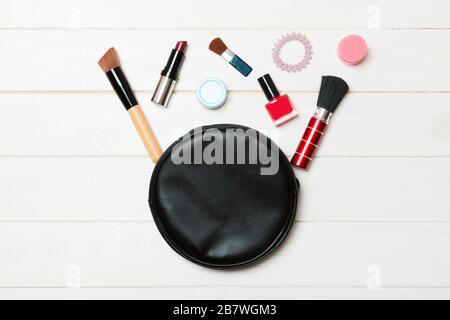 Top view od cosmetics bag with spilled out make up products on wooden background. Beauty concept with empty space for your design. Stock Photo