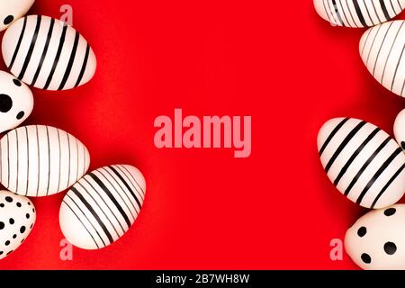 Different graphic hand-painted eggs on bright red background. Easter concept. Place for text. Stock Photo