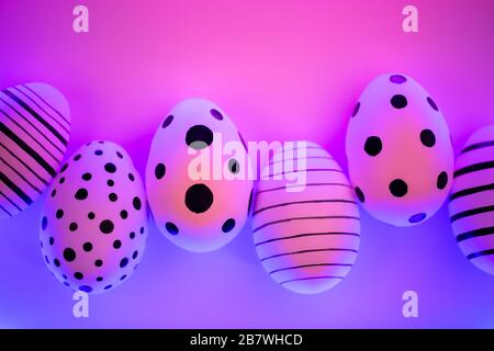 Different graphic hand-painted eggs in Proton Purple neon light. Easter concept. Top view. Stock Photo