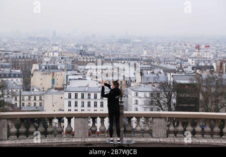 Paris, France. 18th Mar, 2020. A woman wearing mask takes photos while doing exercises at Montmartre in Paris, France, March 18, 2020. French President Emmanuel Macron on March 16 widened steps already taken to fight 'a sanitary war' against the COVID-19 pandemic, ordering border closures, air traffic suspension, tougher restriction on movements and also penalties for offenders. Starting from Tuesday noon and for at least two weeks, people across French cities can only move out for reasons of work, health needs or shopping of necessities. Credit: Gao Jing/Xinhua/Alamy Live News Stock Photo
