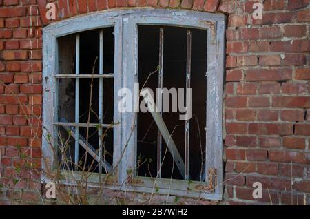A window in a ruined house, the decline of the economy shows dilapidated buildings and ruined windows of former dwellings. Stock Photo