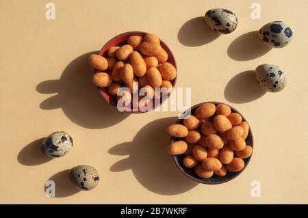 Five eggs and two bowls with nuts with shadows like rabbits on the yellow background. Trendy conceptual minimalistic photo for Easter Holiday 2020 Stock Photo