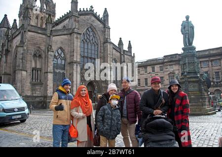 Edinburgh, Scotland, UK. 18th March 2020.  Covid-19 not stopping tourists walking around the Royal Milethis family from Indonesia pose in front of St Giles Cathedral for a photo. Stock Photo