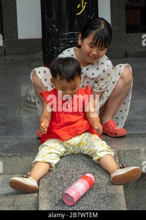 toddler playing with sister, Xian, China Stock Photo