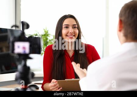 Young woman manager sitting in office and talking with colleague Stock Photo