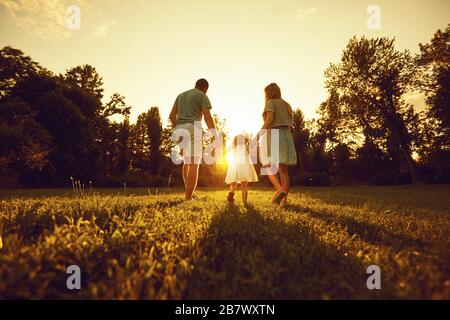 Happy parents with children in the park at sunset. Stock Photo