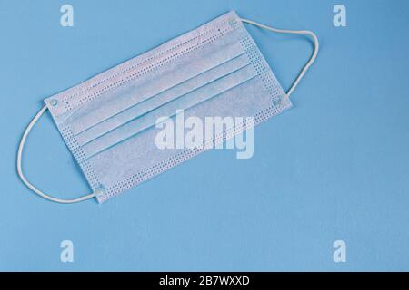 A sanitary mask helps prevent the entry of the Corona virus or other diseases. On a blue background. View from above. Copy space Stock Photo