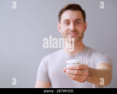 Young man taking care of his skin with a hydration cream and lotion closeup, background. Stock Photo