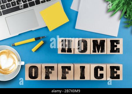 working from home concept, text HOME OFFICE on wood cubes besides laptop computer and notepad on desk Stock Photo