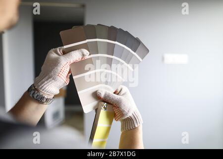Repairmans hands with color palette over grey renovated walls Stock Photo