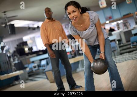 Smiling mid adult woman throwing a bowling ball. Stock Photo