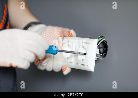 Repairman in gloves fixing socket with screwdriver Stock Photo