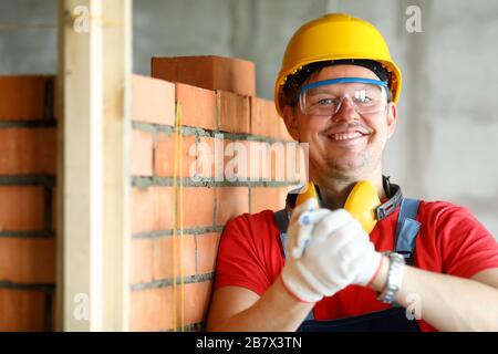 Worker at construction site making friendship gesture in protective gloves Stock Photo