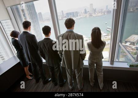 Group of colleagues looking out a window together in their office building. Stock Photo