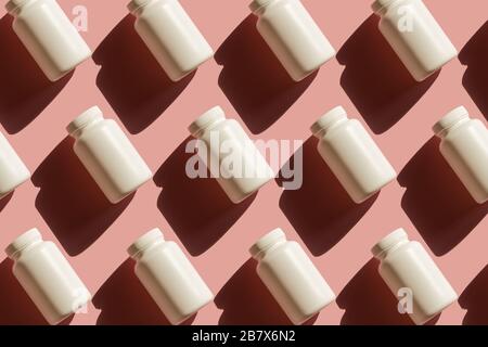 Repeating white cans of pills on a pink background, background in pop art style, medical concept Stock Photo