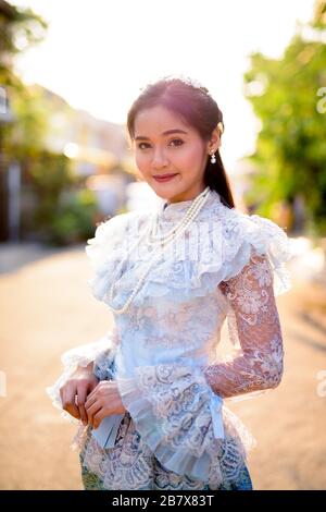 Young beautiful Asian woman wearing Thai traditional clothes outdoors Stock Photo