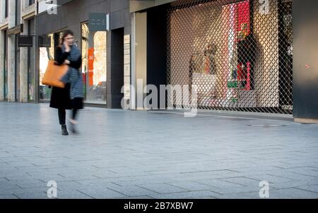 Duesseldorf, Germany. 18th Mar, 2020. A woman walks past closed shops on Königsalle. With a few exceptions, all shops in North Rhine-Westphalia are to remain closed from 18.03.2020. Credit: Martin Gerten/dpa/Alamy Live News Credit: dpa picture alliance/Alamy Live News Stock Photo