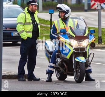 Braunschweig, Germany, March 8., 2020: Policeman on motorcycle with flashing blue light and patrolman on foot talking at the roadside Stock Photo