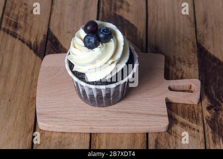 Chocolate muffin with white cream and blueberry. Stock Photo