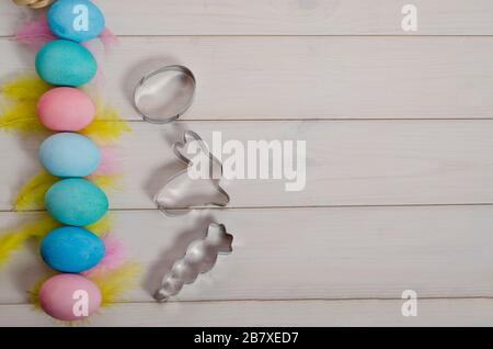 Easter baking. Multi-colored Easter eggs and cookie cutters in the form of a rabbit, eggs, carrots with copy space. Happy easter. Flat lay. Stock Photo