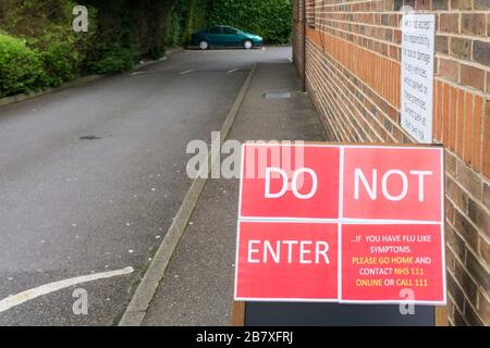 18 March 2020. Bromley, South London, UK.  Sign on a doctor's surgery warns people not to enter with 'flu like symptoms.  A response to the Covid 19 Coronavirus pandemic.  Credit UrbanImages-news/Alamy Stock Photo