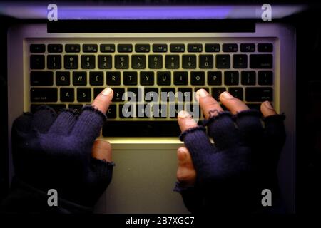 hooded hacker stealing data from laptop at night  Stock Photo