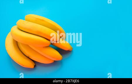 A bunch of yellow bananas on a blue background. Copy space. Stock Photo