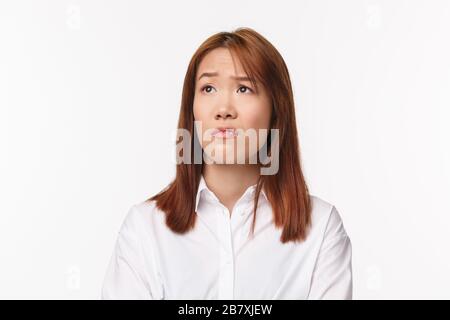 Close-up portrait of skeptical young asian girl grimacing aversion and judgemental looking left, raising eyebrow surprised and unimpressed with Stock Photo