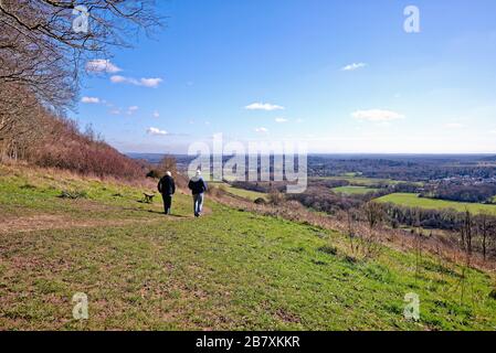 An elderly couple walking on a footpath on Ranmore Common on a sunny spring day, Surrey Hills Dorking England UK Stock Photo