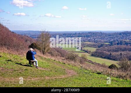 An elderly couple seated on bench enjoying the view at Ranmore Common in the Surrey Hills on a sunny spring day Dorking Surrey England UK Stock Photo