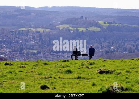 Two male ramblers sitting on bench looking at the view of Westcott and Leith Hill on a spring day from Ranmore Common, Surrey Hills Dorking England UK Stock Photo