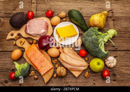 Trendy ketogenic diet products set. Paleo, pegan low carbs nutrition. Meat, fish, cheese, fruits and vegetables. Wooden boards background Stock Photo