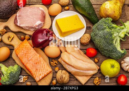 Trendy ketogenic diet products set. Paleo, pegan low carbs nutrition. Meat, fish, cheese, fruits and vegetables. Wooden boards background Stock Photo