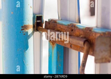 Rusty old slide bolt or tower bolt on a worn green door. Stock Photo
