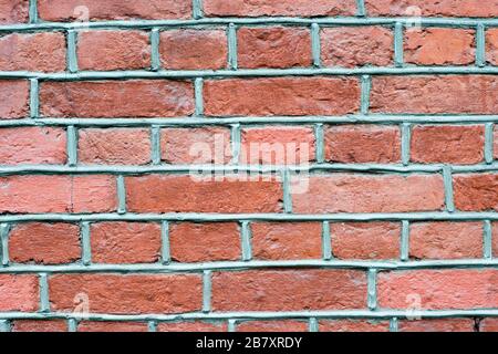 The brick wall is red with a brown tint with voluminous gray joints of the solution. Textured background. Stock Photo