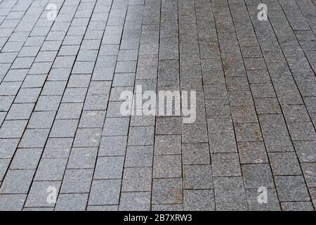 The sidewalk is paved with granite with uneven lighting gradient. Background. Stock Photo