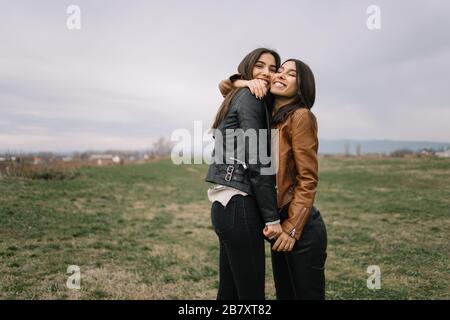 Two happy sisters cuddling in the park Stock Photo