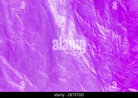 Close up texture of bright purple plastic garbage bag. Crumpled cellophane. Violet polyethylene film background. Ecology problem. Stock Photo