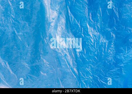 Close up texture of bright blue plastic garbage bag. Crumpled cellophane. Violet polyethylene film background. Ecology problem. Stock Photo