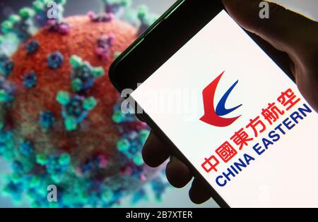 In this photo illustration the China Eastern airline logo seen displayed on a smartphone with a computer model of the COVID-19 coronavirus on the background. Stock Photo